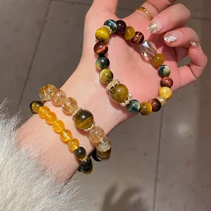Hand wearing elegant beaded bracelets featuring tiger eye stones and clear quartz crystals