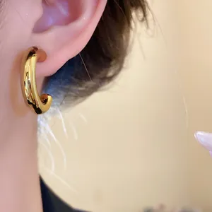 Close-up of minimalist gold-plated chunky C-shaped hoop earring for women