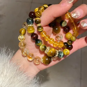 Hand holding multiple tiger eye and crystal beaded bracelets with gold accents