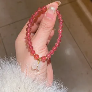 Detailed macro view of a red agate beaded bracelet with a moonstone pendant and gold spacers