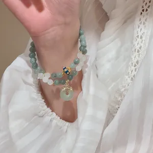 Close-up of elegant double-layered beaded bracelet with light green pendant on wrist
