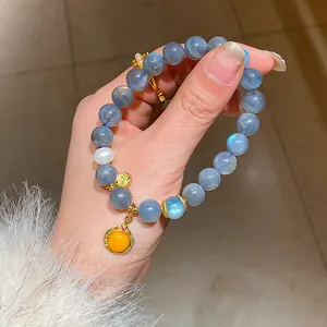Close-up detail of a beaded moonstone bracelet featuring a decorative golden charm