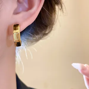 Elegant close-up of a minimalist gold C-shaped earring on model ear for detail view.
