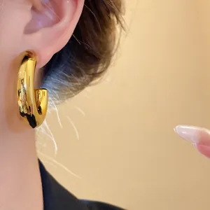 Close-up of chunky gold C-shaped hoop earring with a brilliant high-shine finish.