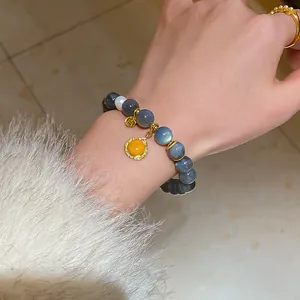 Close-up detail of new Chinese style beaded bracelet with gold fortune charms on a model's wrist