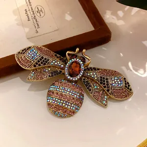 Close-up view of a vintage bee brooch featuring colorful rhinestones and amber crystal