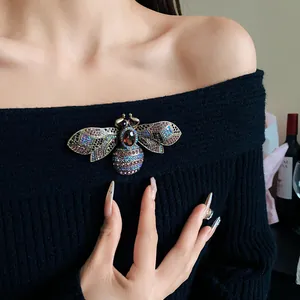 Close-up of a vintage court-style bee brooch with colorful rhinestones on black fabric