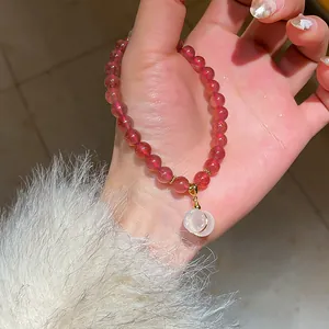 A detailed macro view of a red agate beaded bracelet with an elegant moonstone pendant