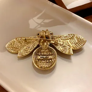 Vintage gold-tone bee brooch with detailed textured wings and secure metal safety pin back closure