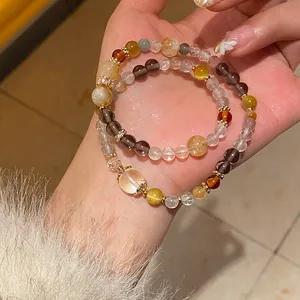 Detail of handmade moonstone and red agate beaded bracelets with gold accents on hand
