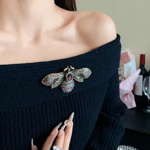 Close-up detail of an ornate vintage bee brooch with colorful rhinestones on black.