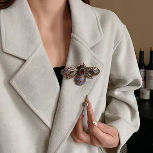 Detail of a luxury ornate rhinestone bee brooch accessory pinned on a wool coat