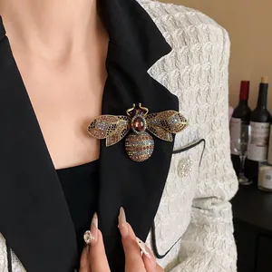 Detailed view of an ornate vintage rhinestone bee brooch on a black blazer lapel.