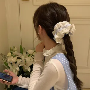 Close-up of a blue and white ruffled lace hair scrunchie worn on a braided ponytail