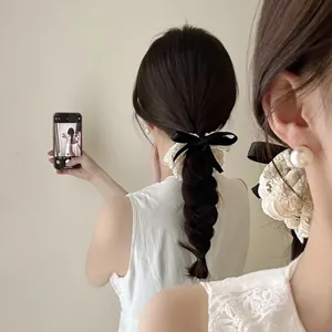 Korean style cream lace scrunchie with a black velvet bow shown in a mirror selfie