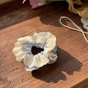Detailed view of a stylish light blue fabric scrunchie with delicate cream lace trim