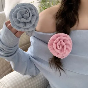 Detailed view of pink and blue floral fabric scrunchies on a model's hair and hand.