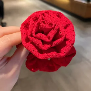 Close-up detail of a vibrant red fabric rose hair scrunchie with lace patterns