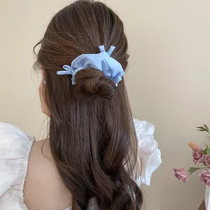 Back view of a woman wearing a light blue ruffled fabric scrunchie in a bun style