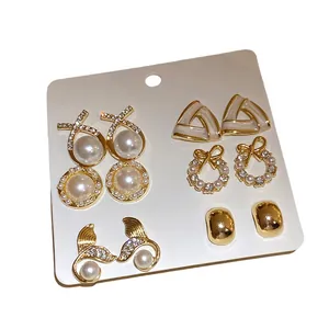 Elegant 5-pair set of gold-toned pearl and rhinestone stud earrings on a display card