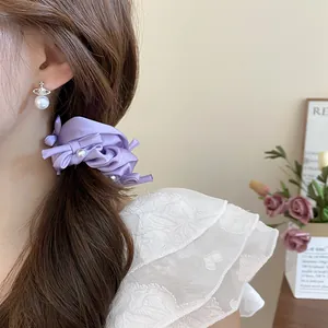 Detail view of a purple pleated fabric scrunchie with pearl and bow accents on hair