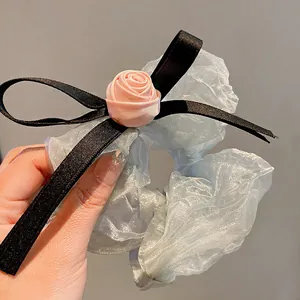 Close-up of light blue organza scrunchie with pink fabric rose and black ribbon bow.