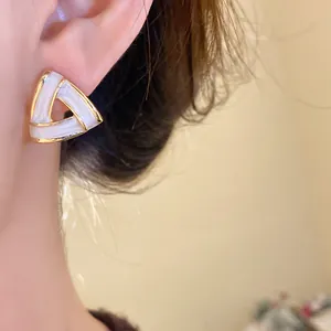 Close-up detail of elegant French vintage triangle earrings with gold and white finish