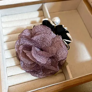 Close-up detail of a dusty purple fabric flower hair scrunchie with large pearl bead