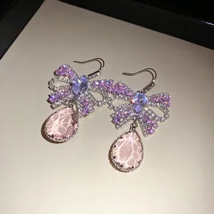 Elegante Schleifenohrringe mit lila Zirkonia und rosa Kristall-Tropfenanhänger.