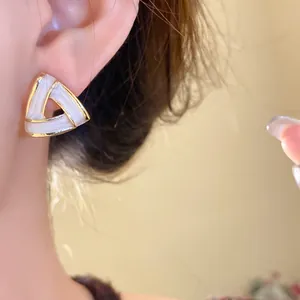 Close-up of elegant French vintage triangle stud earring with gold trim and white enamel