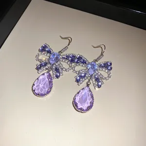 Nahaufnahme von lila Zirkon-Schmetterlingsohrringen mit eleganten Kristallanhängern