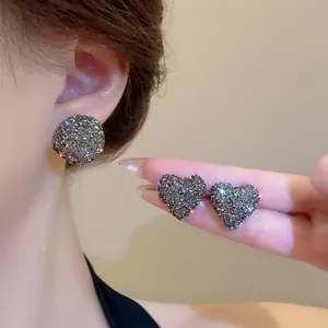 Elegante primo piano di orecchini a lobo scintillanti a cuore e tondi con strass