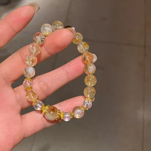 Primo piano di un bracciale di perle in quarzo citrino con distanziatori floreali dorati.