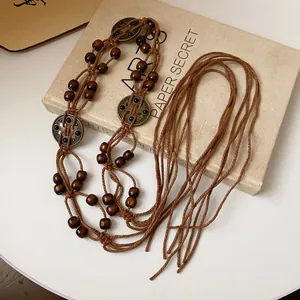 Macro detail of a bohemian style braided rope waist chain with wooden beads and medallions.