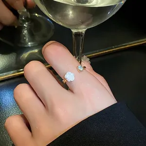 Elegant gold-tone open ring featuring a white camellia flower and a sparkling zircon detail.