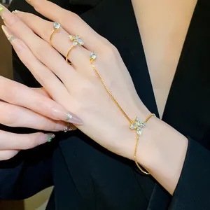 Primo piano di un elegante bracciale con anello a fiore in zircone dorato su mano.
