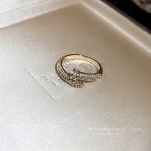 Elegant gold-plated snake-shaped open ring with pave zircon crystals on beige silk