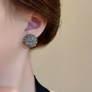 Dettaglio di eleganti orecchini a lobo con sfera di cristallo scintillante indossati