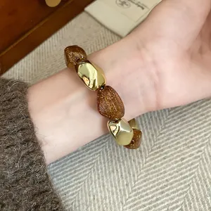 Primo piano di un bracciale elastico vintage con perle dorate e marroni glitterate