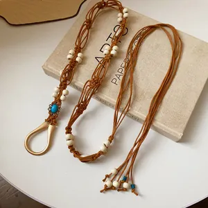 Detailed view of bohemian braided hemp waist chain with white wooden beads and blue stone