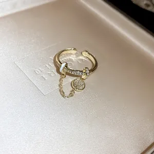 Close-up of a luxury gold-plated open ring featuring zircon stones and a dangling charm.