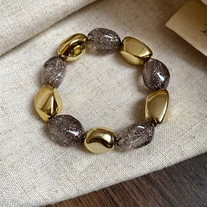 Dettaglio di un bracciale elastico vintage in acrilico con perle dorate e glitterate