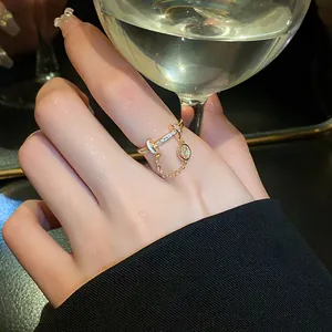 Detailed macro shot of a gold-toned ring with pavé zircon stones and a delicate chain.