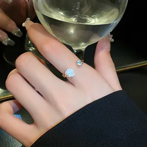 Elegant detail shot of zircon flower open ring on finger with wine glass background.