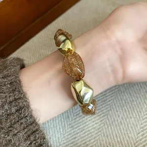 Primo piano dettagliato del braccialetto elastico vintage con perle acriliche oro e ambra