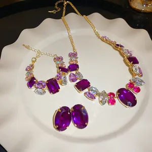 Close-up detail of luxury vintage jewelry set featuring purple rhinestones and gold chains
