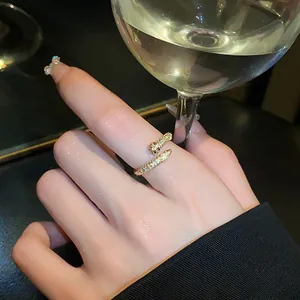 Elegant gold zircon open ring detail shown on a hand holding a crystal wine glass
