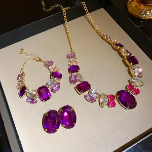 Detailed close-up view of vintage jewelry set featuring purple and pink crystals in gold