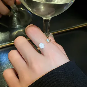 Detail of elegant white rose and zircon open ring worn on finger in a stylish setting