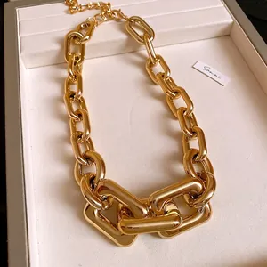 Close-up of high-quality chunky gold-plated metal link necklace on elegant jewelry display tray